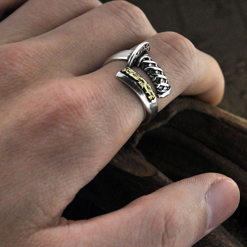 Silver ring with gold accents on a finger against a dark background